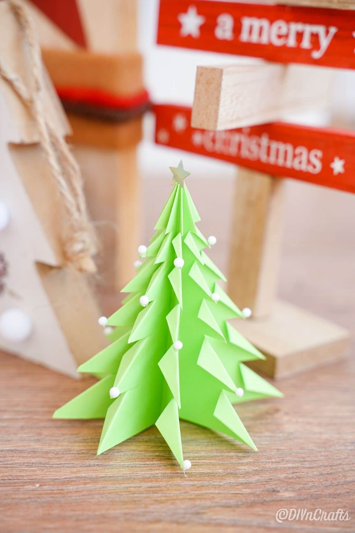 papirnato 3d božično drevo na mizi z lesenim znakom