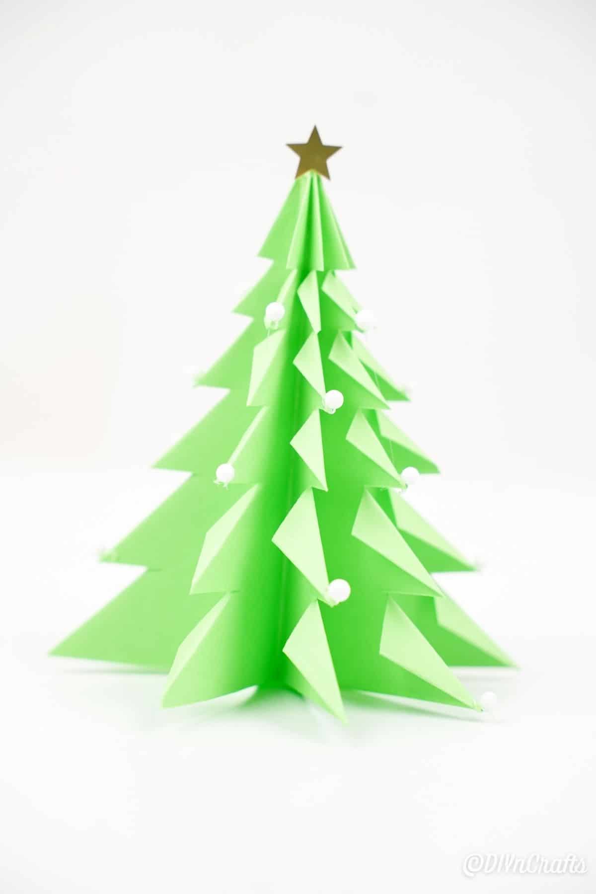 3D origami božično drevo v zelenem papirju na beli mizi