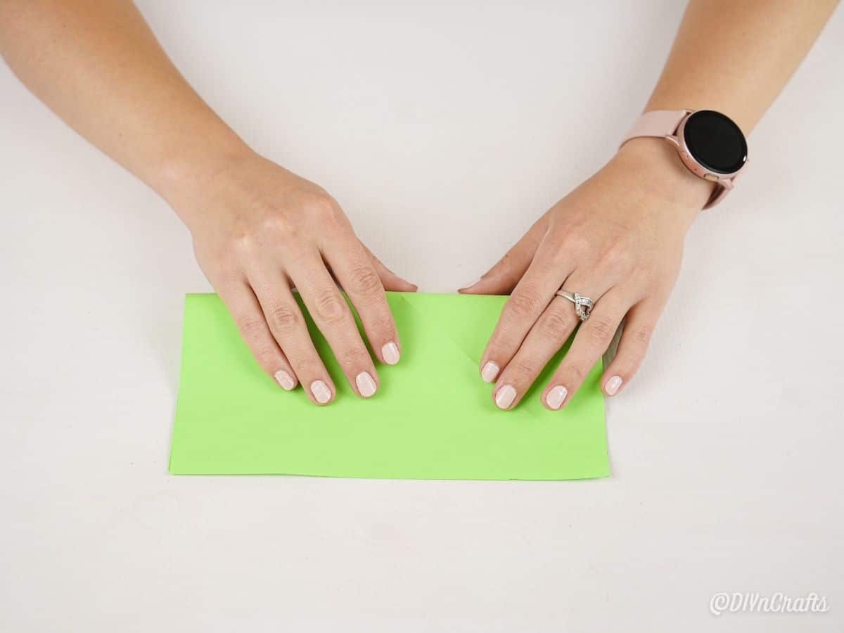 hands folding green paper in half