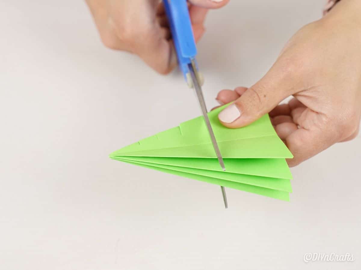 scissors cutting into green tree paper