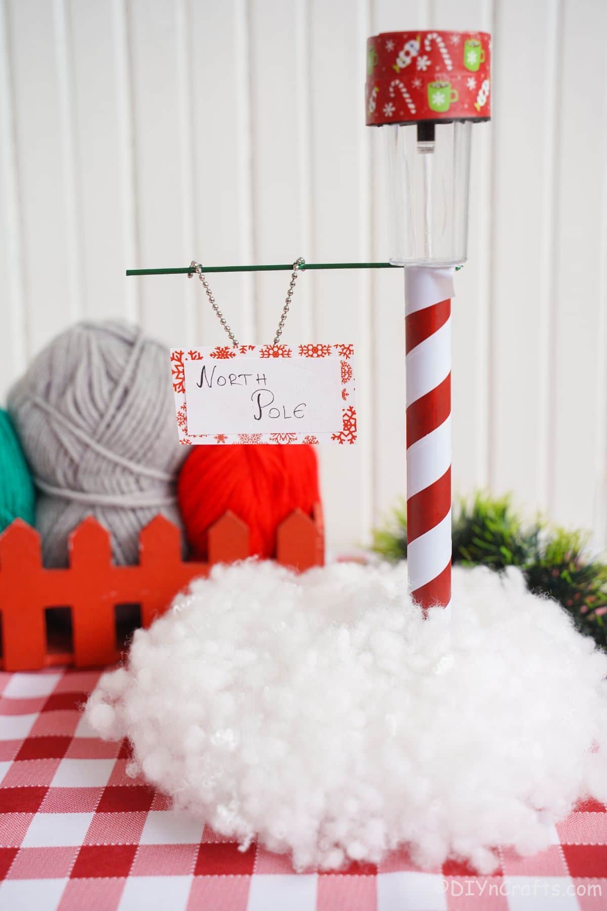 red and white checked tablecloth beneath miniature north pole sign