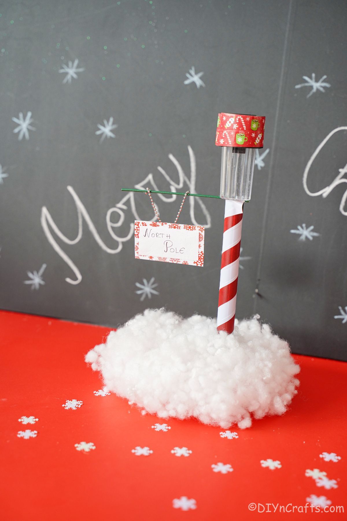 north pole street sign on red table with chalkboard in background
