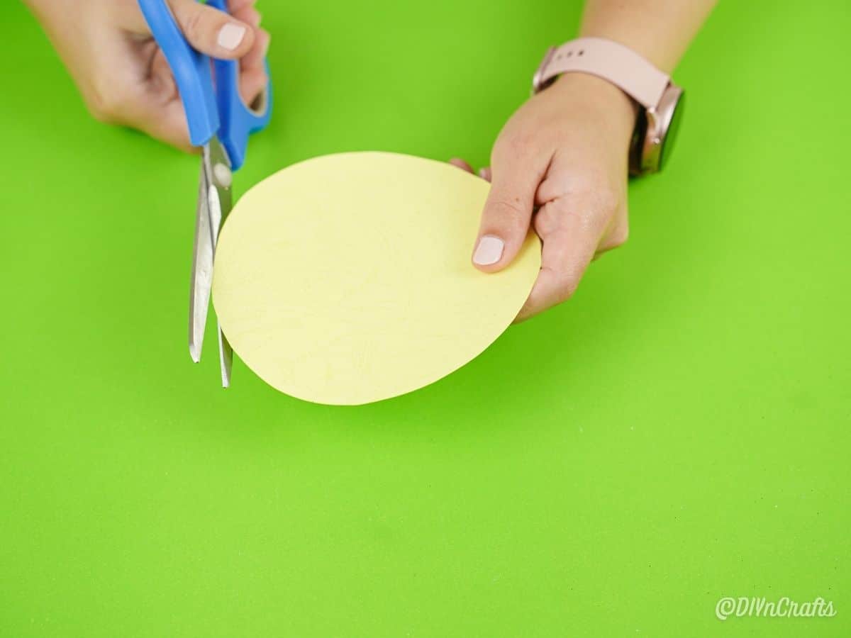 hand cutting yellow paper circle