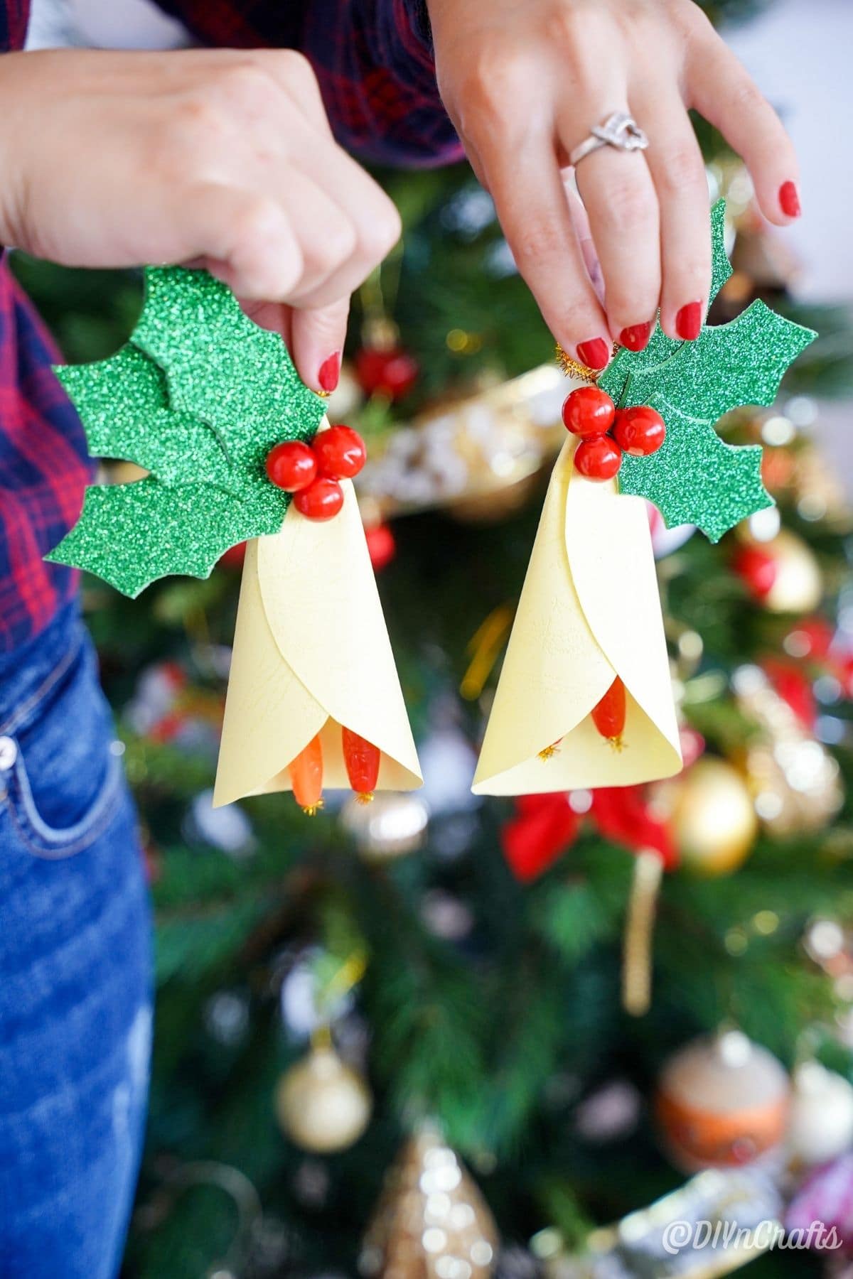 ladies hands holding paper ornaments by Christmas tree
