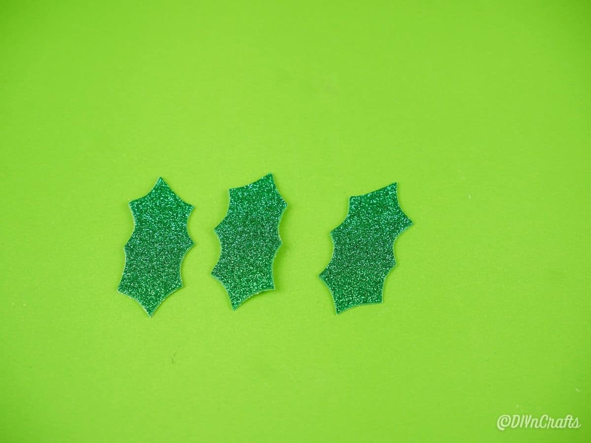 three green glitter holly leaves