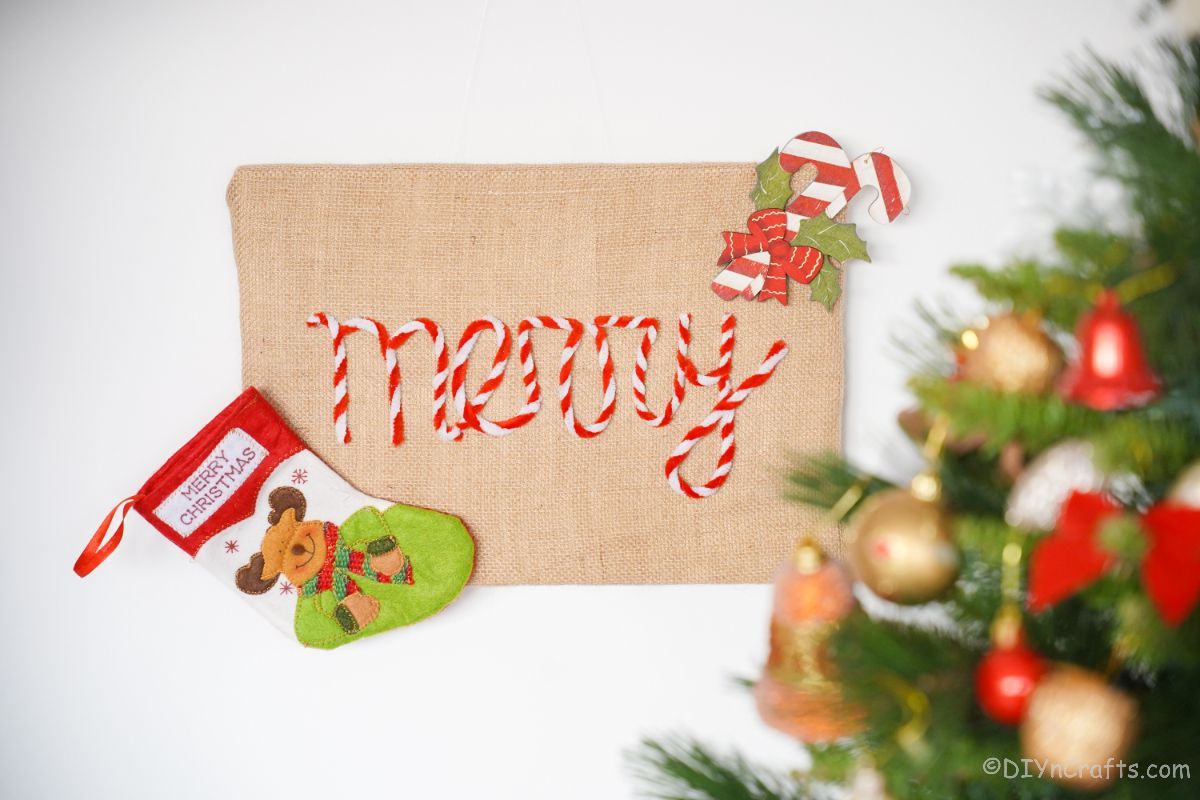 white wall by christmas tree with burlap merry sign