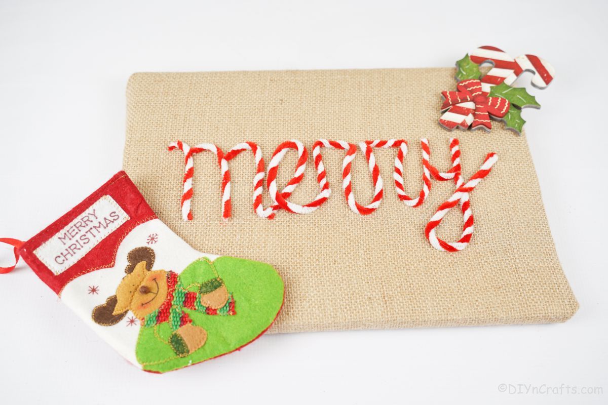 burlap sign that says merry and has mini stocking on white table