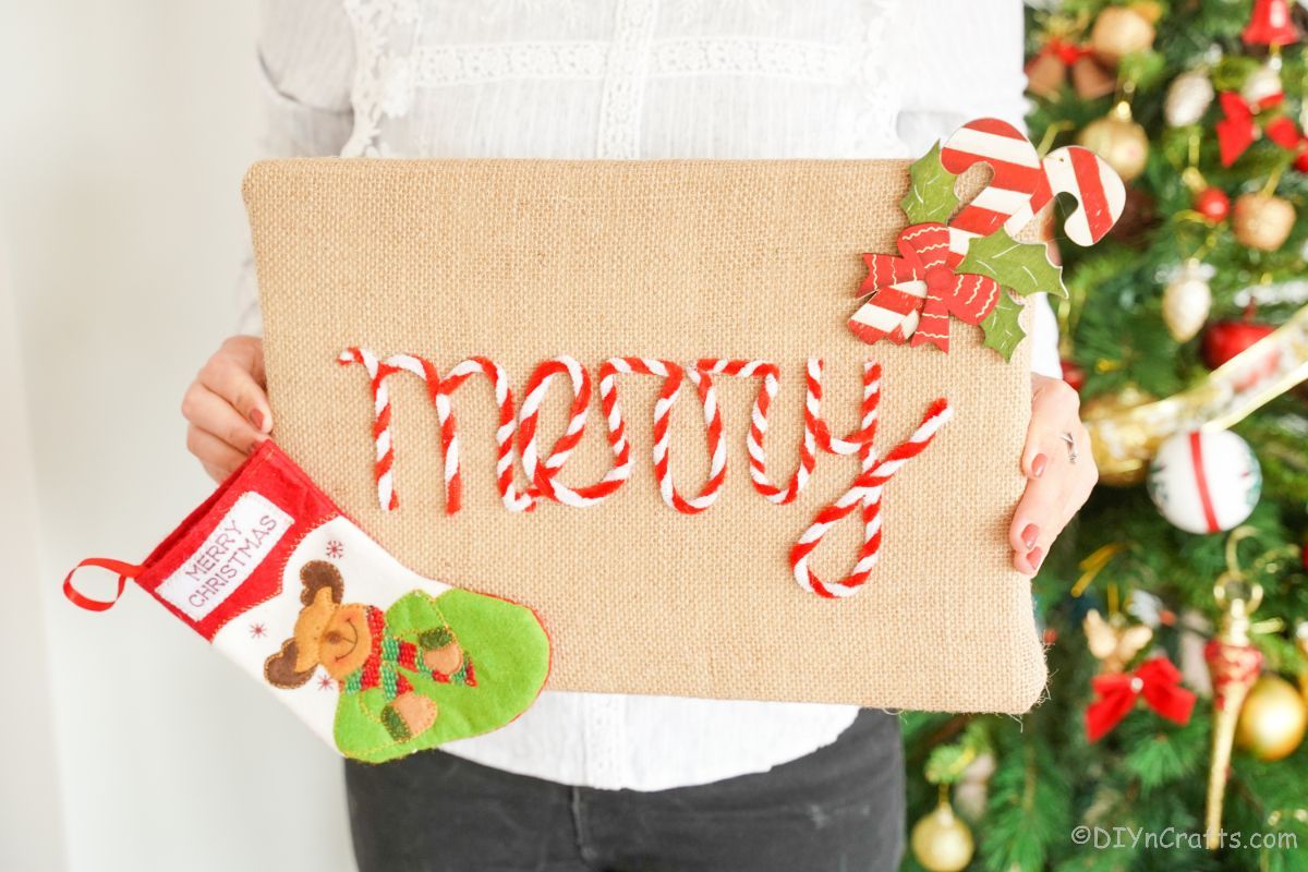 burlap Christmas sign held by person in white sweater