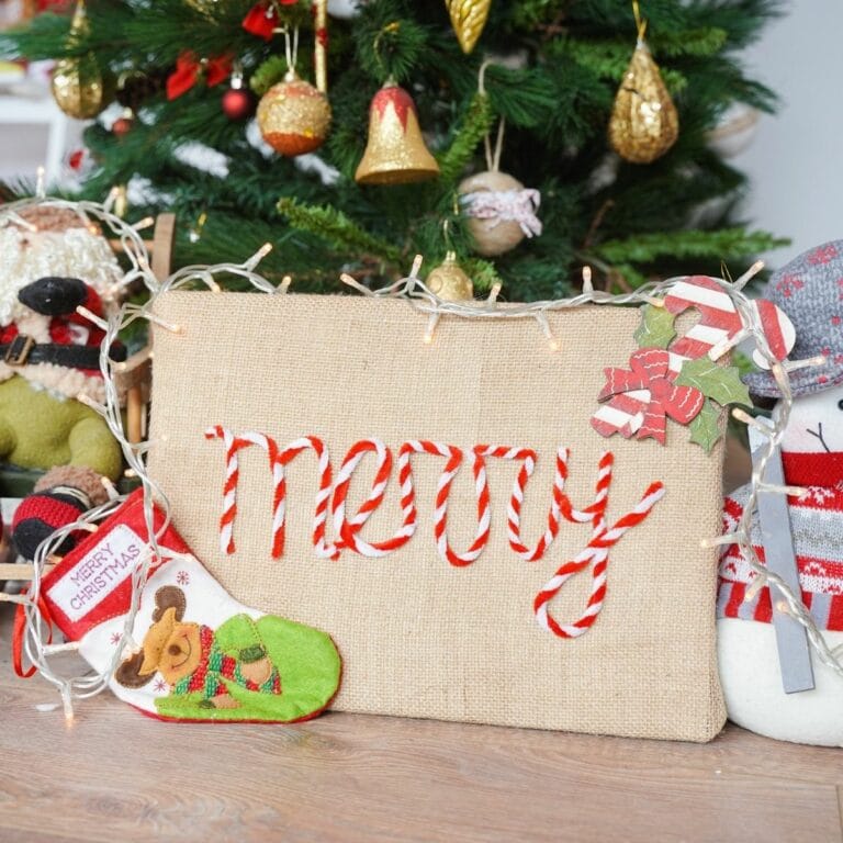 burlap sign with the word Merry in front of christmas tree