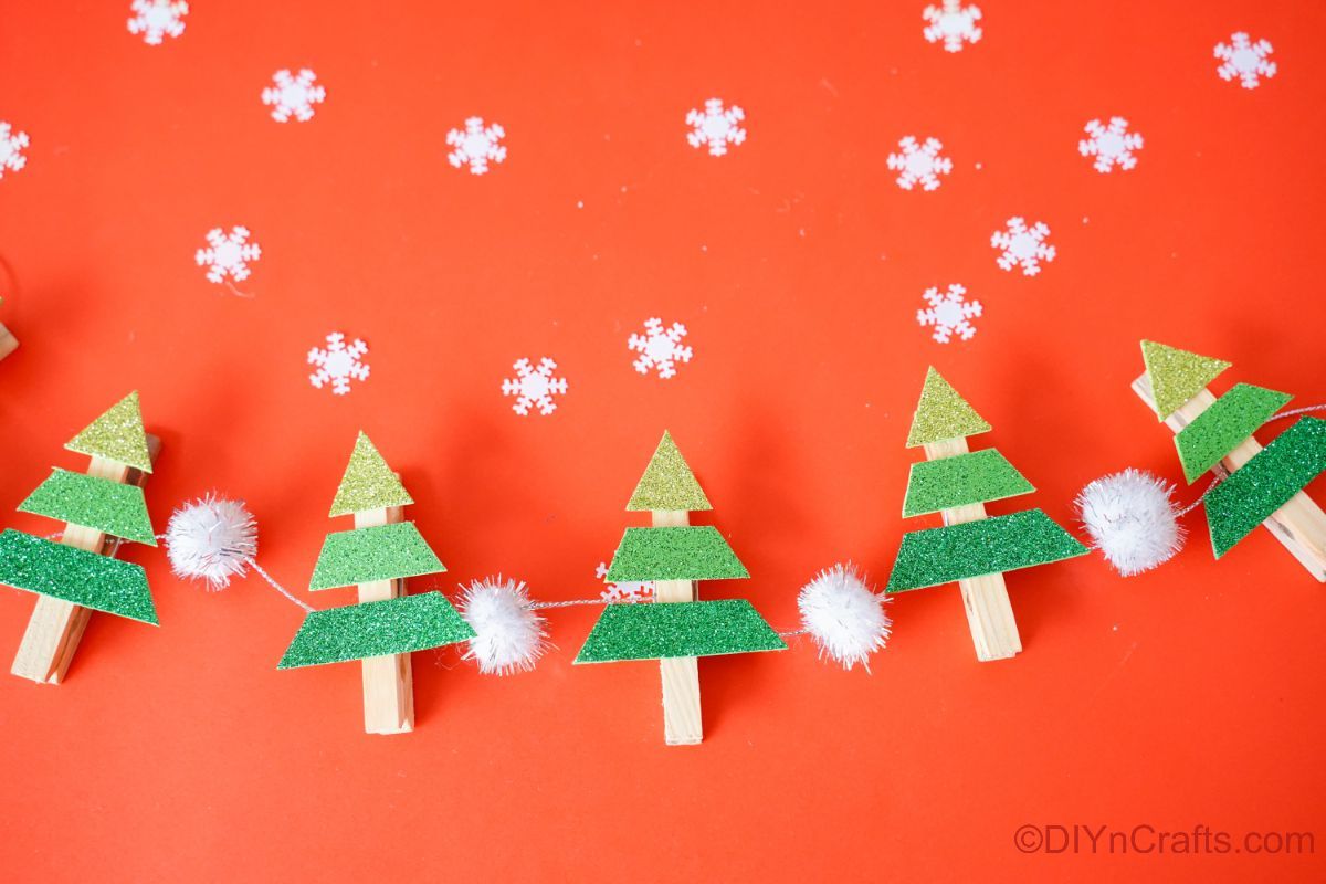 clothespin mini trees on white garland laying on red table