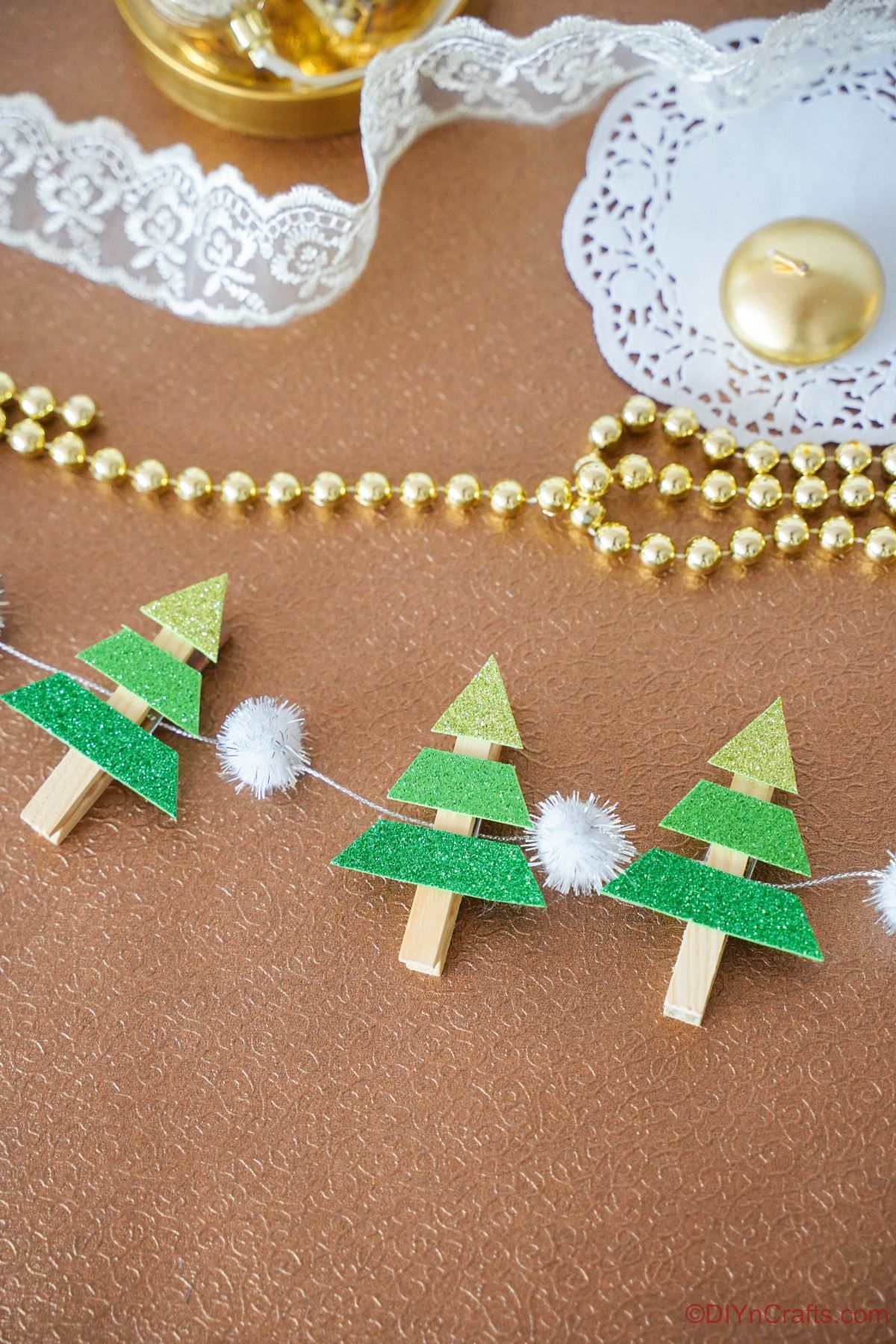 mini tree garland on brown table by lace and beads