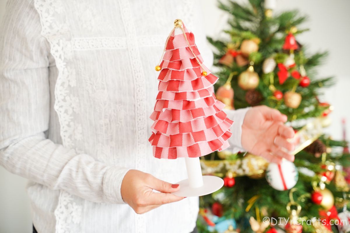 woman in white sweater holding red plaid fabric tree