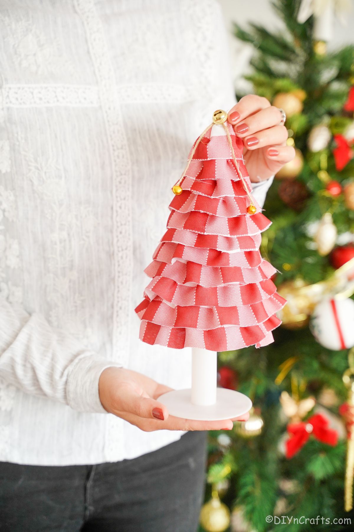 woman holding fabric christmas tree in front of holiday tree