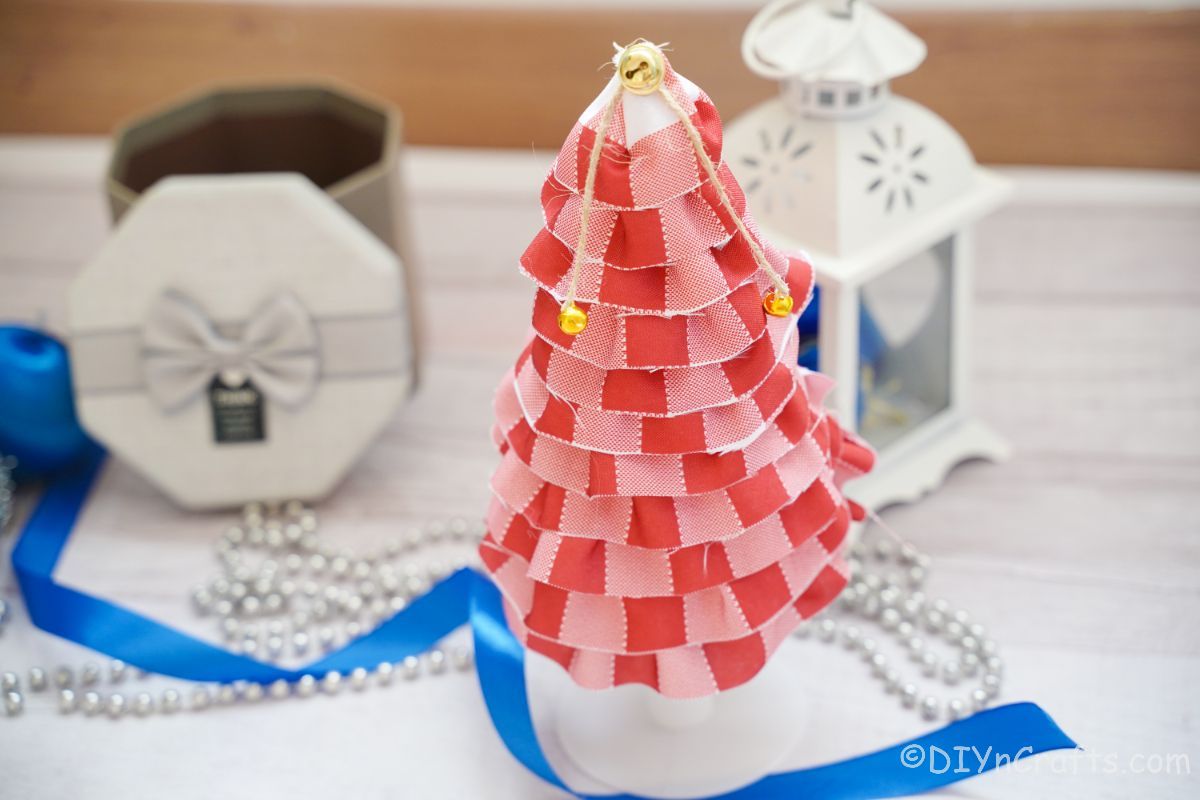 blue ribbon on white table by fabric christmas tree