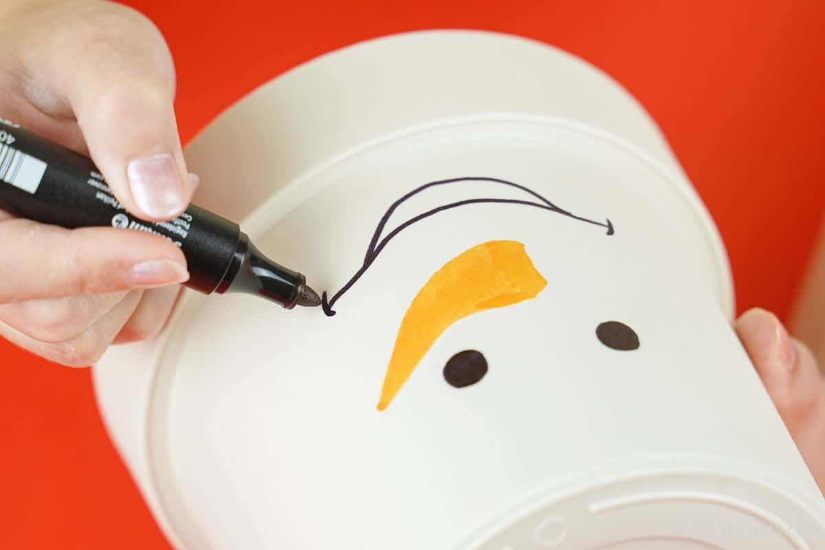 hand using black marker to draw smile on white flower pot