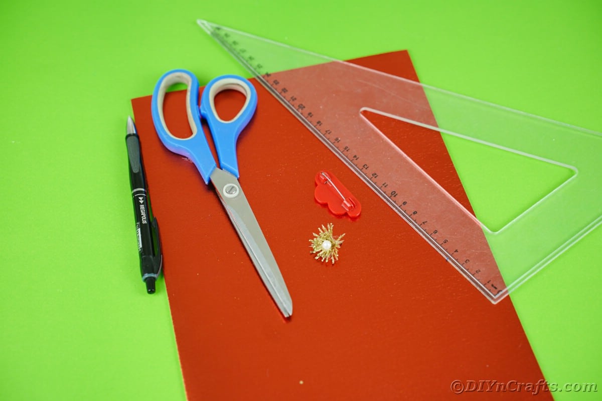 red paper on green table with blue scissors and ruler