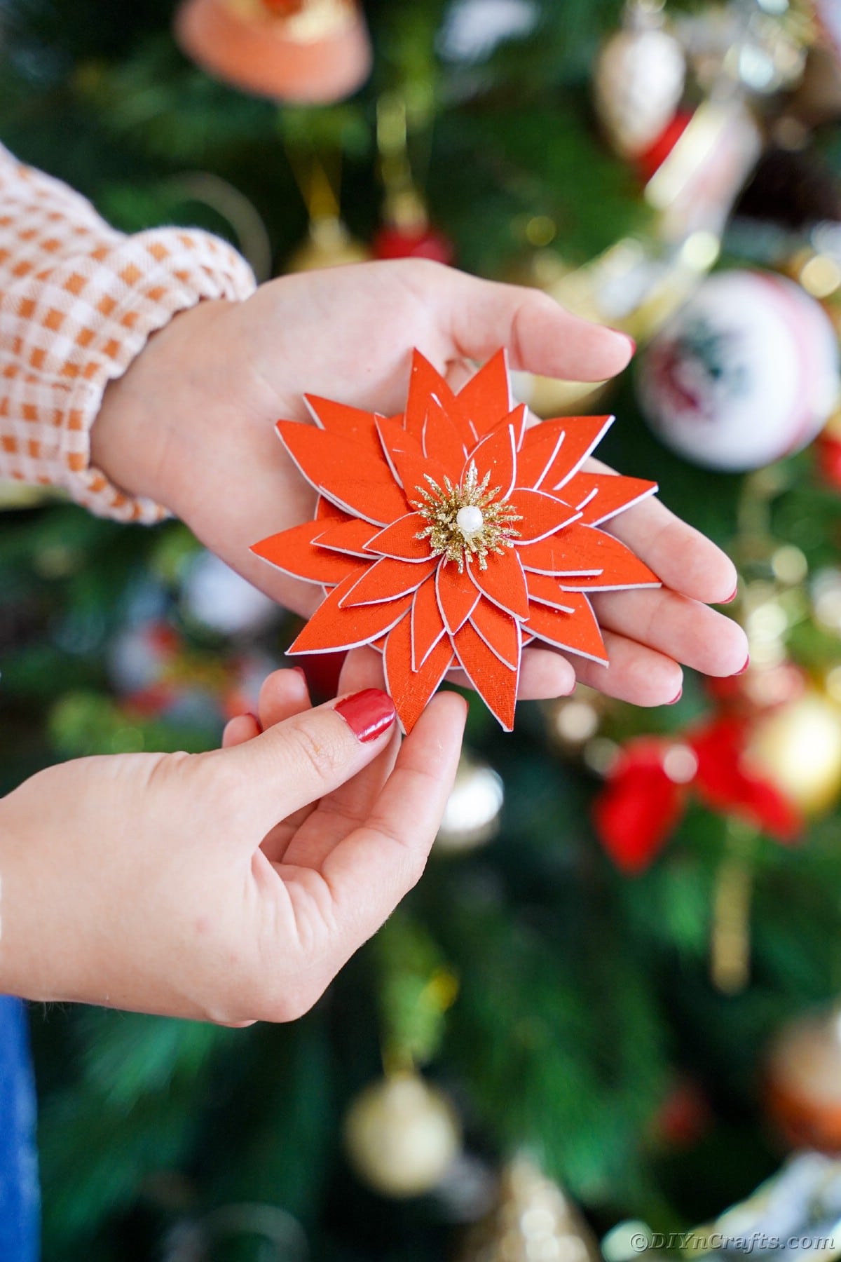woman in front of Christmas tree holding a foam poinsettia