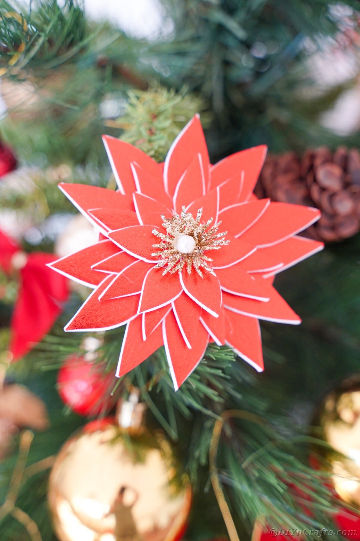 poinsettia ornament hanging on holiday tree