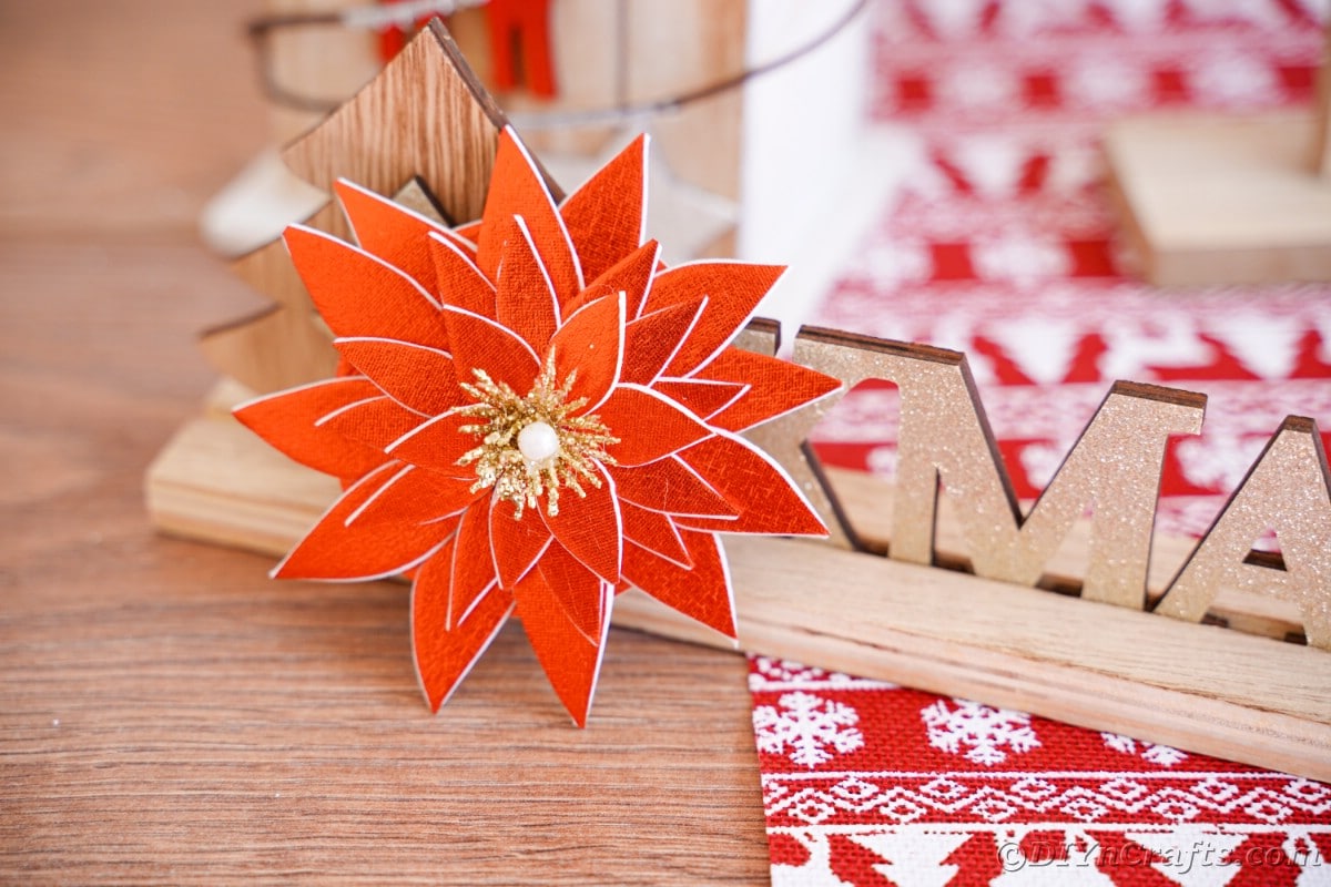 foam poinsettia on wooden sign by red and white holiday paper