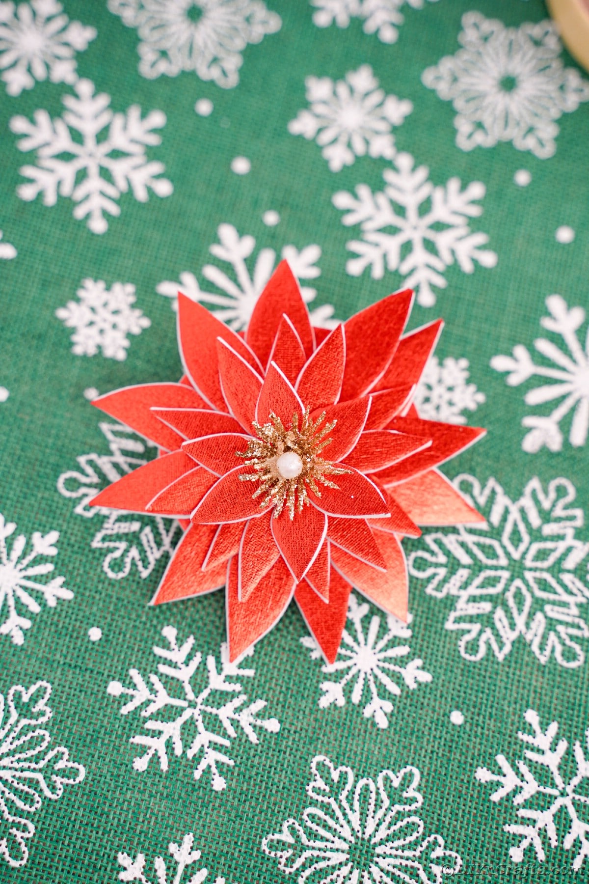 green and white snowflake paper with fake flower on top