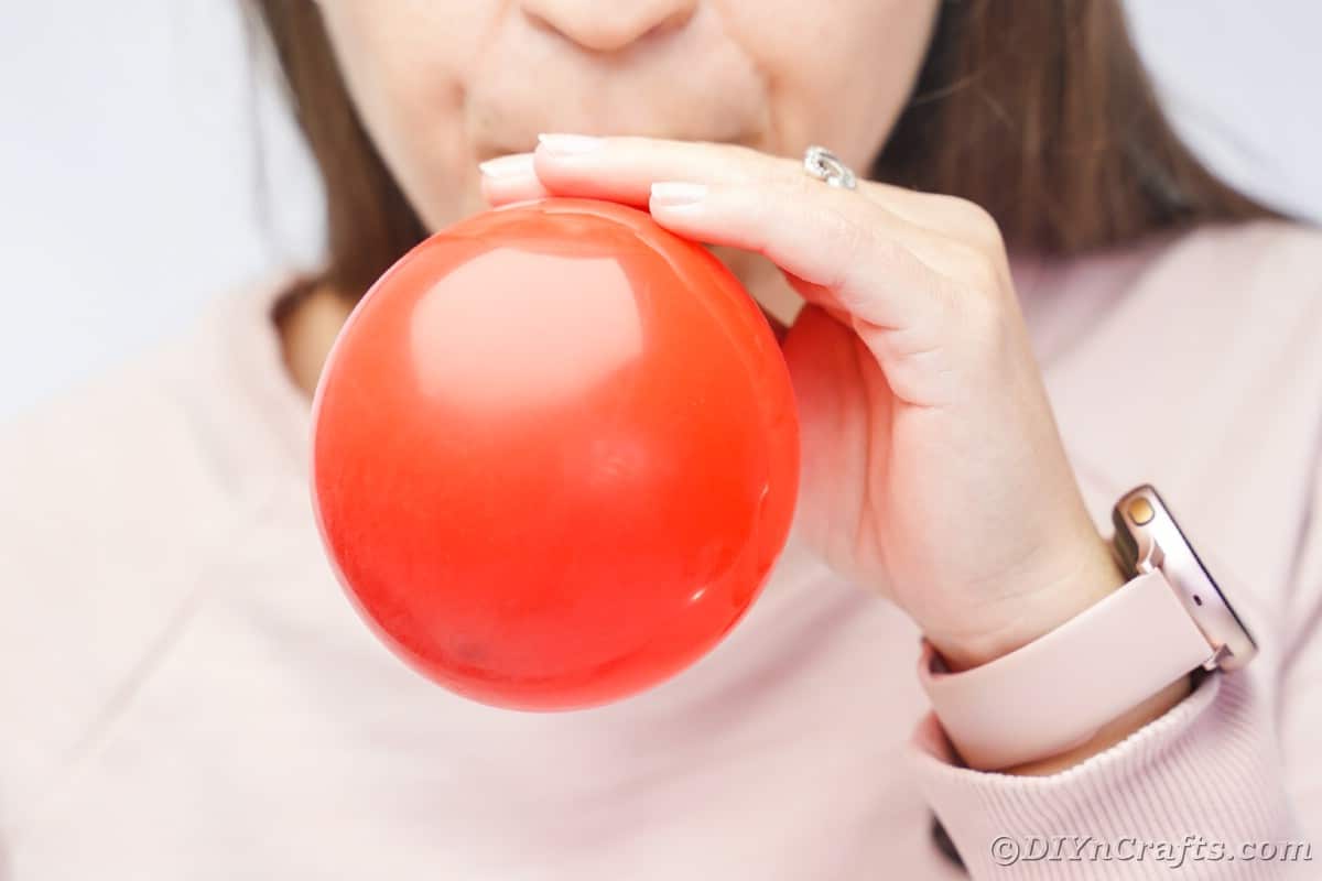 woman blowing up red balloon