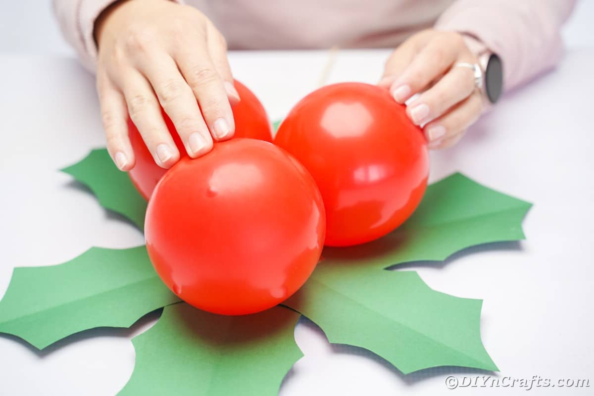 lady holding red balloons on top of green paper leaves