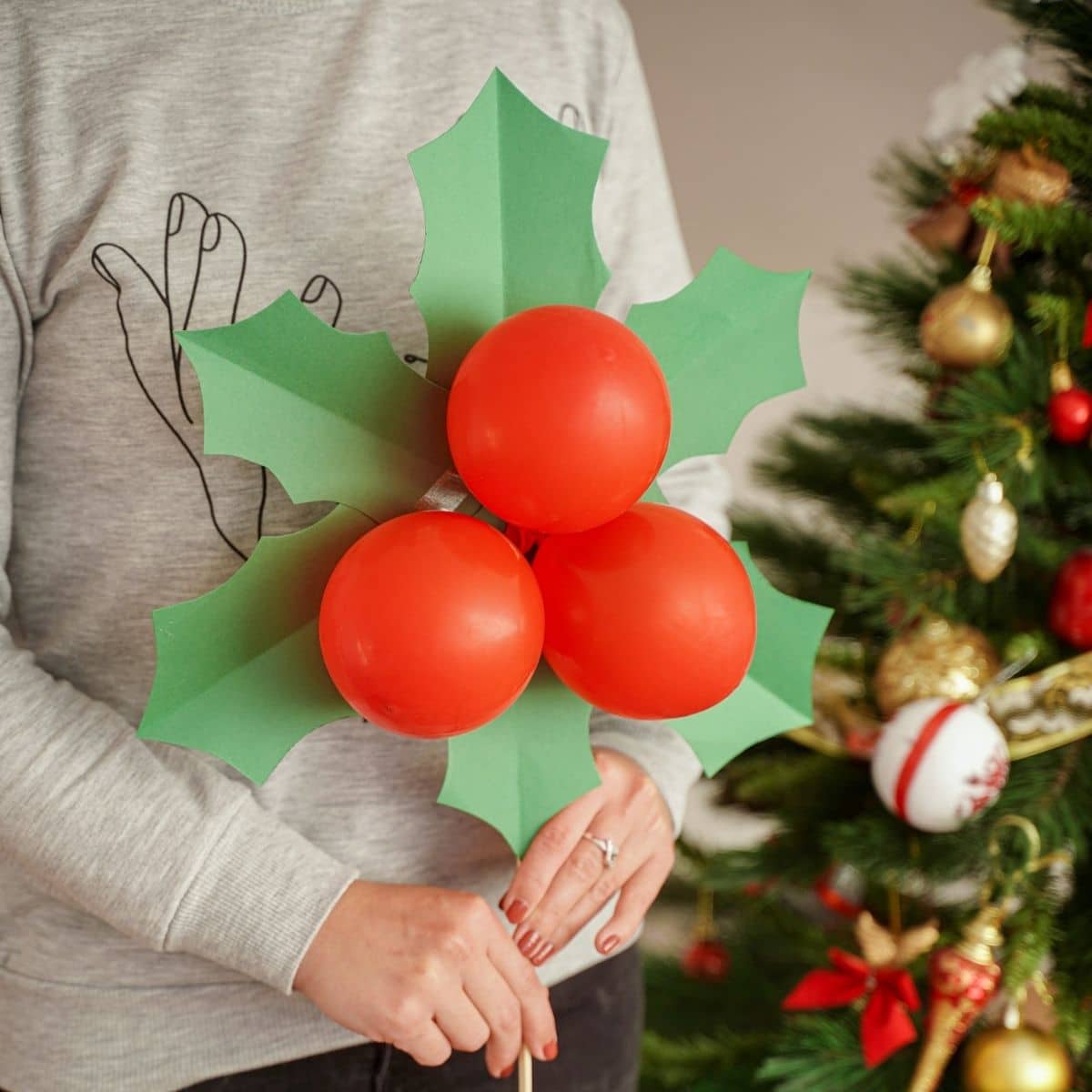 woman holding giant Christmas decoration by tree