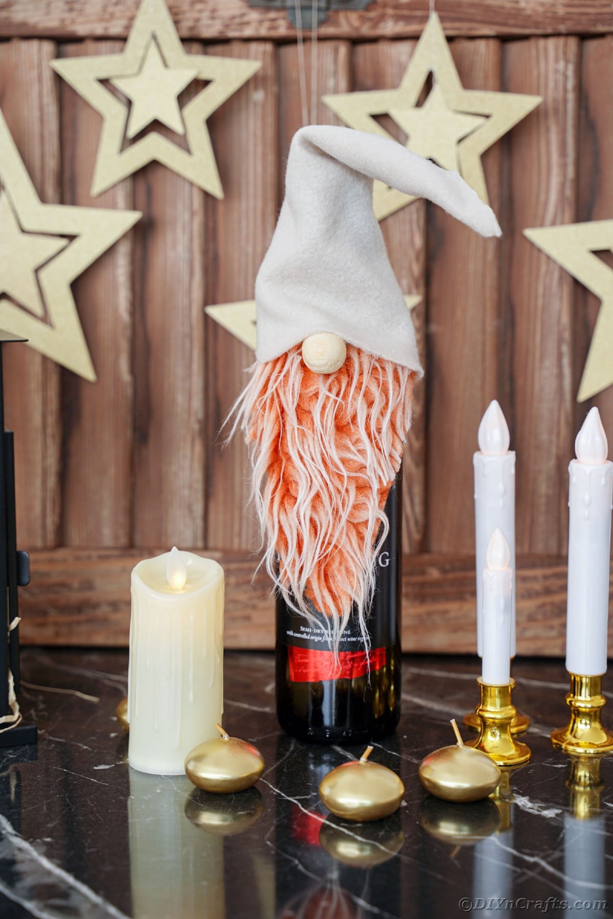 gnome on top of wine bottle on table with candles