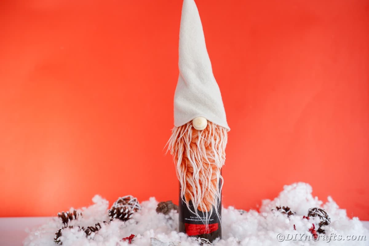 gnome with cream hat and orange beard in front of red wall