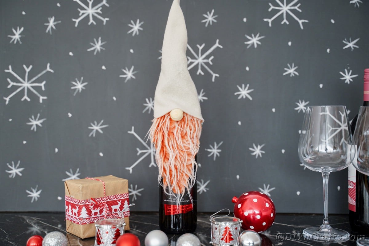 wine bottle with gnome on top in front of chalkboard