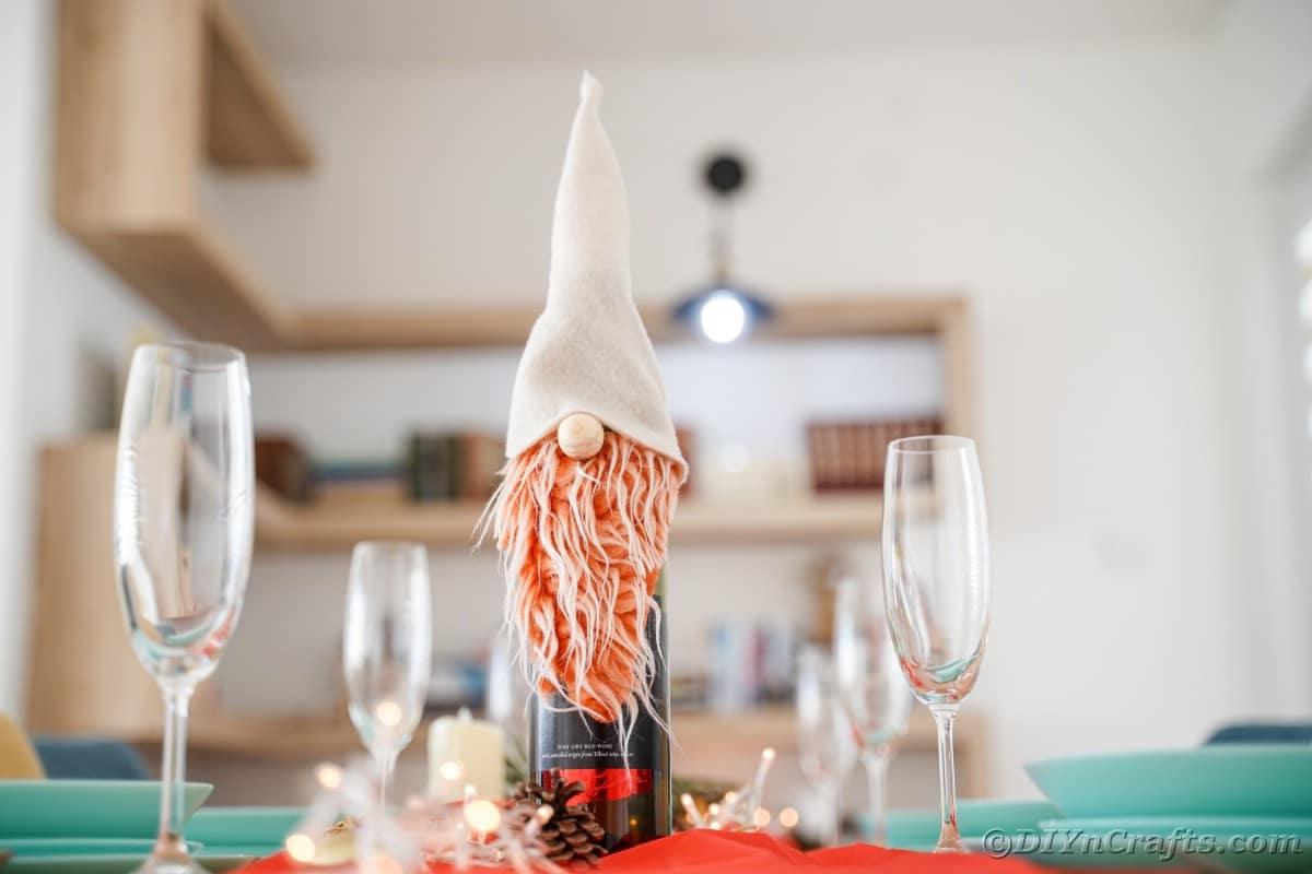 gnome on wine bottle on table by blue plates