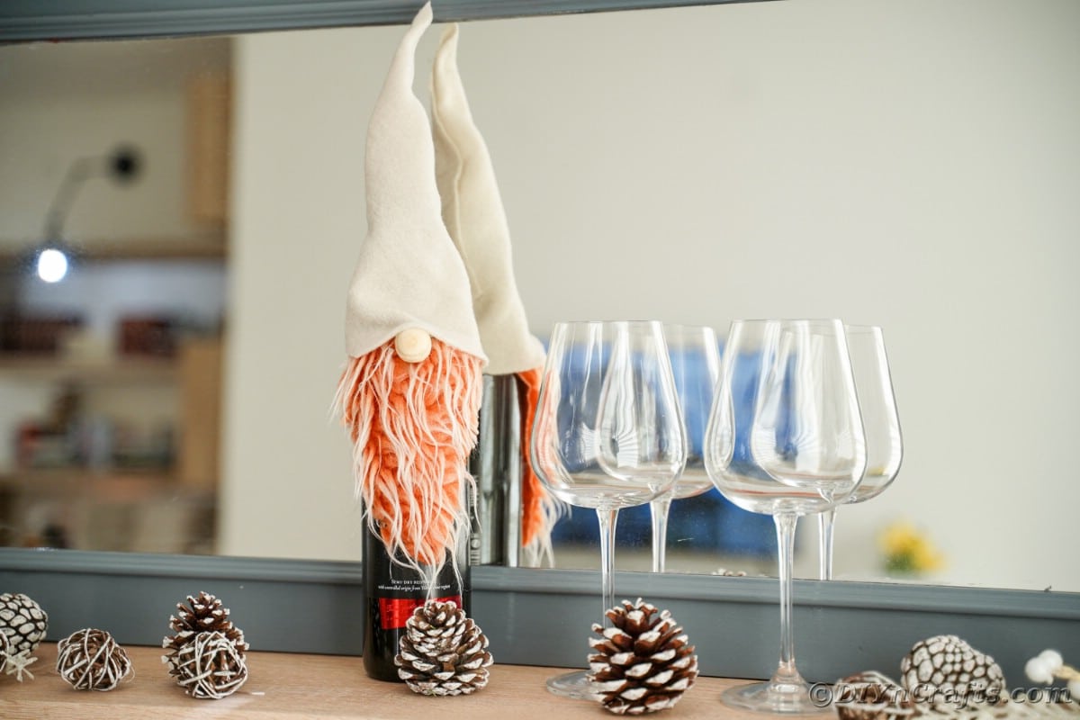 mirror with wine glasses and gnome on wine bottle in front