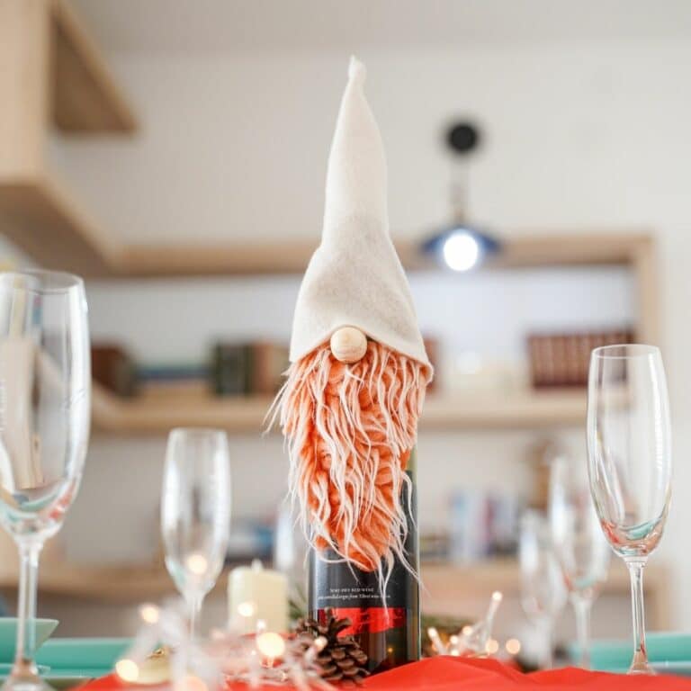 wine bottle with gnome cover on red tablecloth by wine glasses