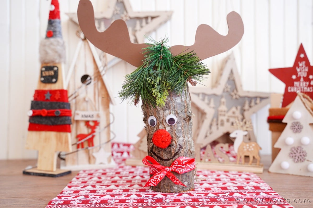 log with antlers and red nose on table with red and white paper