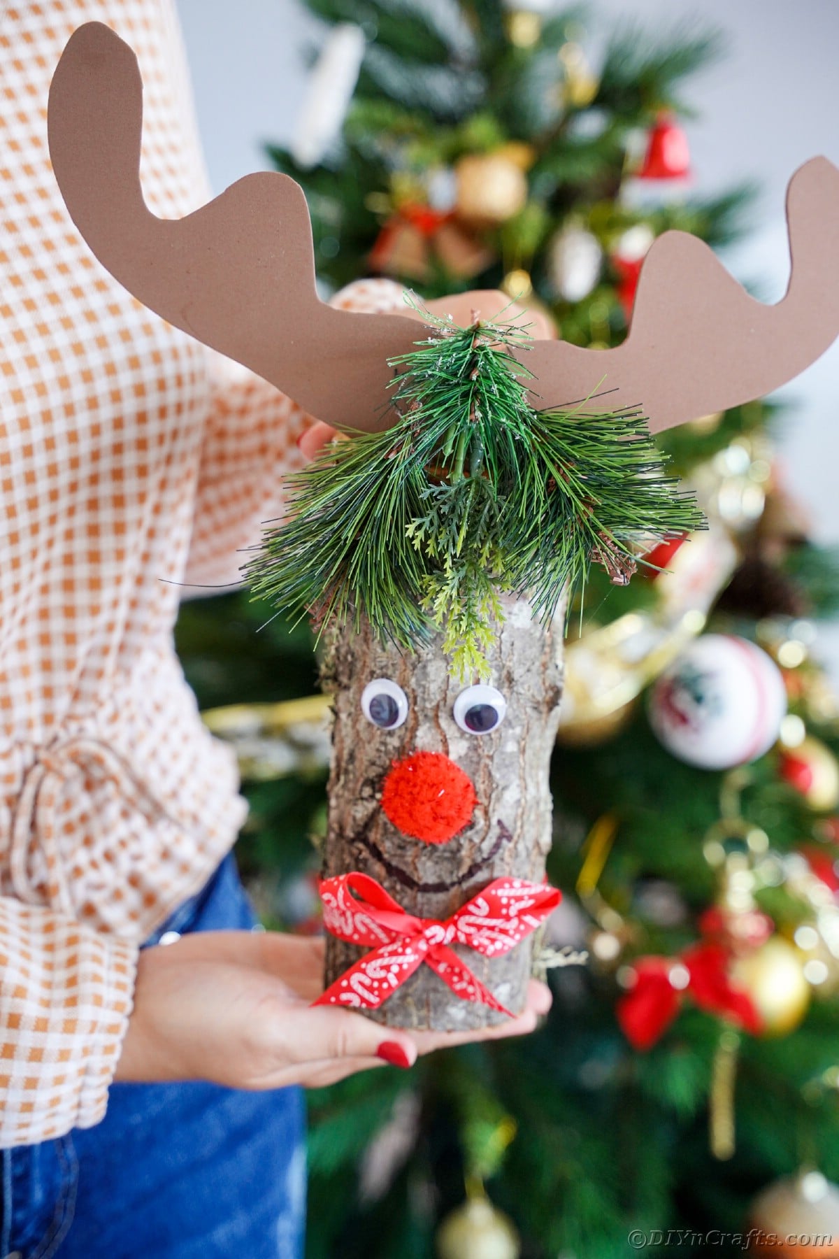 reindeer decoration being held in front of tree
