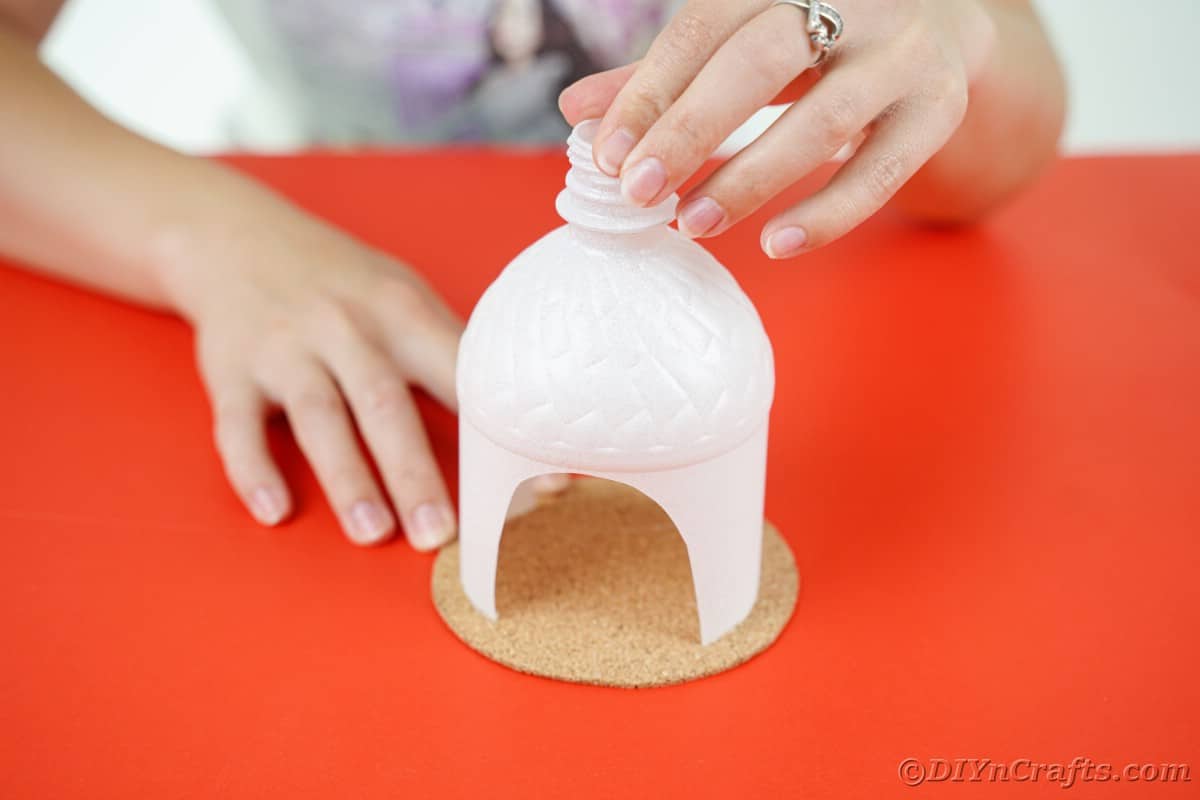 hand gluing plastic bottle onto cork round
