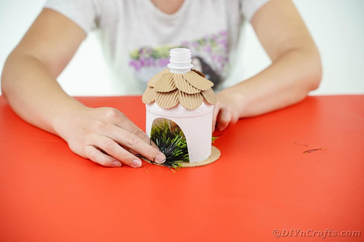 lady with hands adding greenery inside white bottle house
