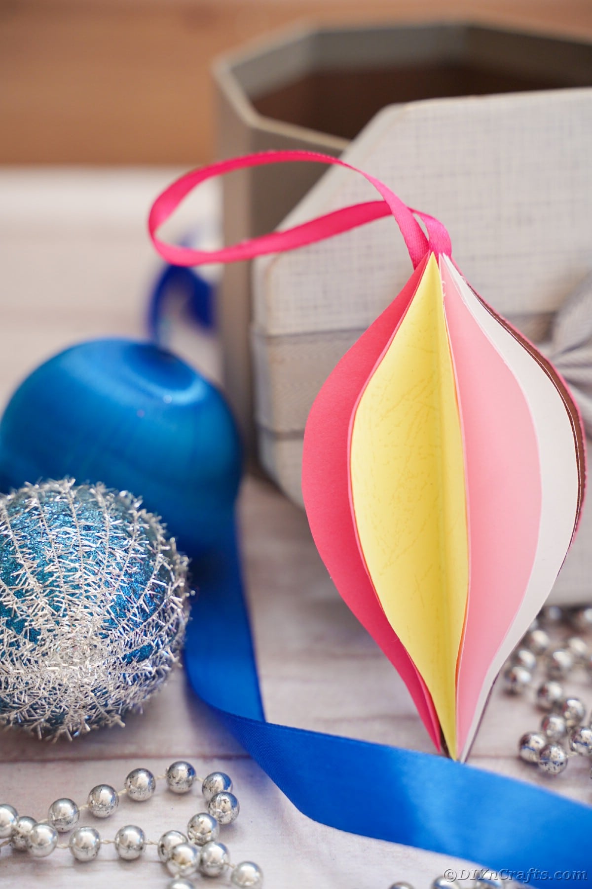 pink and yellow paper ornament in front of blue holiday decor