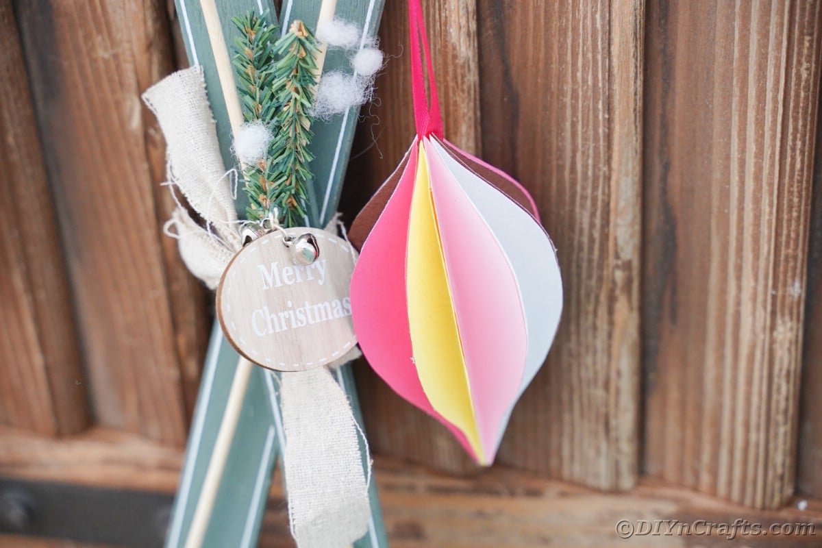 pink and yellow paper ornament hanging in front of wood