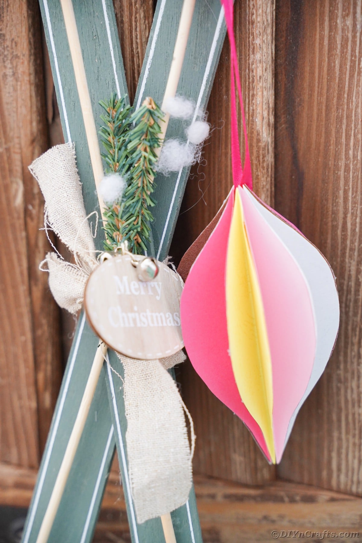 teardrop paper ornament hanging in front of fake snow skis