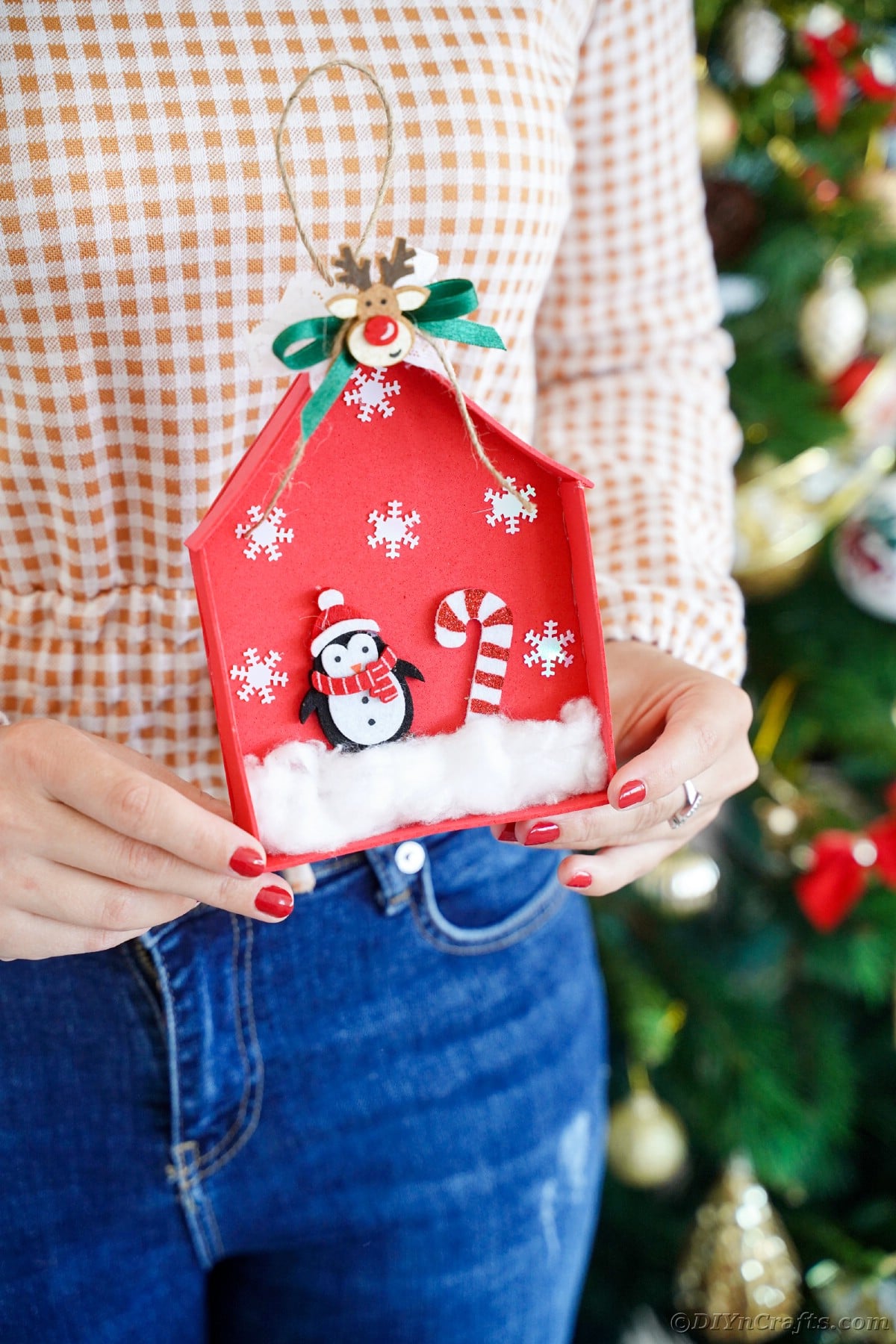 red penguin house ornament being held by woman wearing jeans