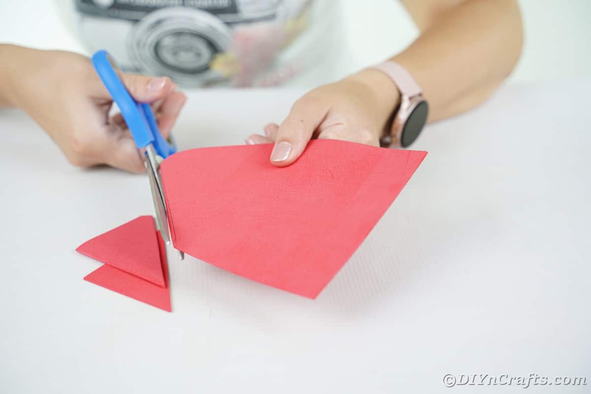 lady using blue scissors to cut a red house out of foam