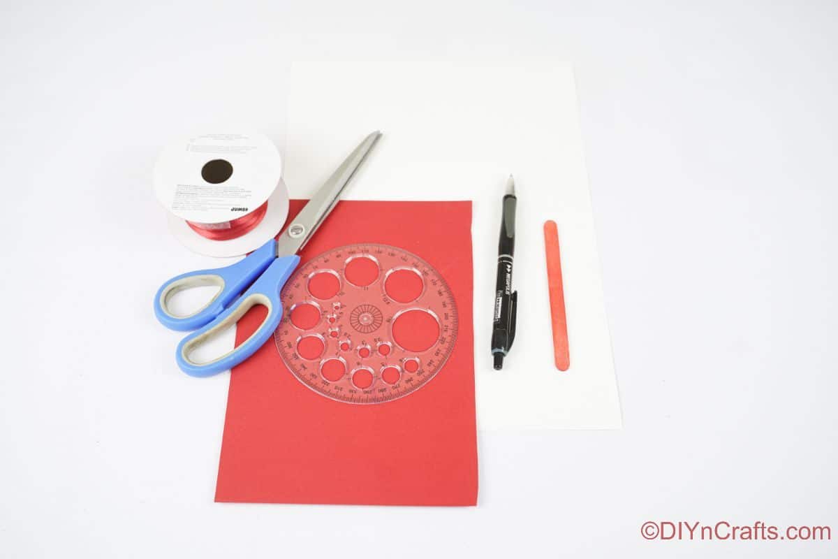 red paper scissors and ribbon on white table