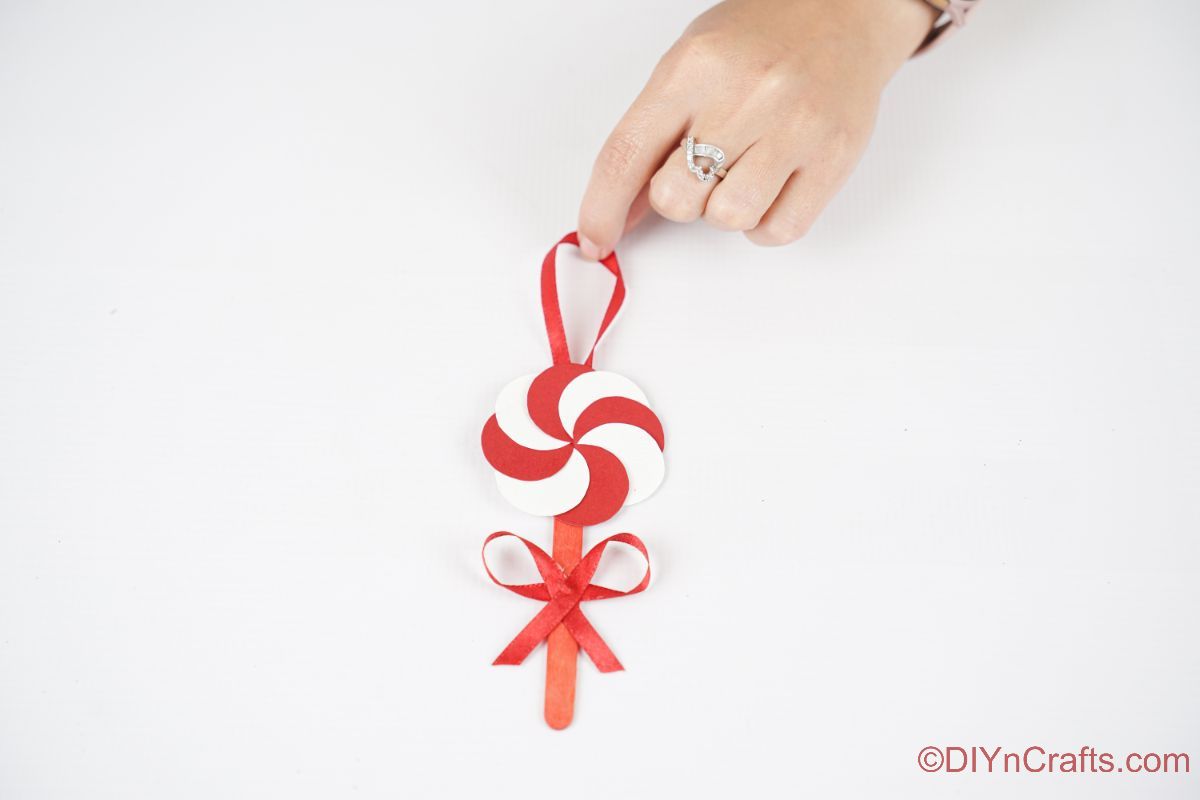 hand holding peppermint candy ornament on white table