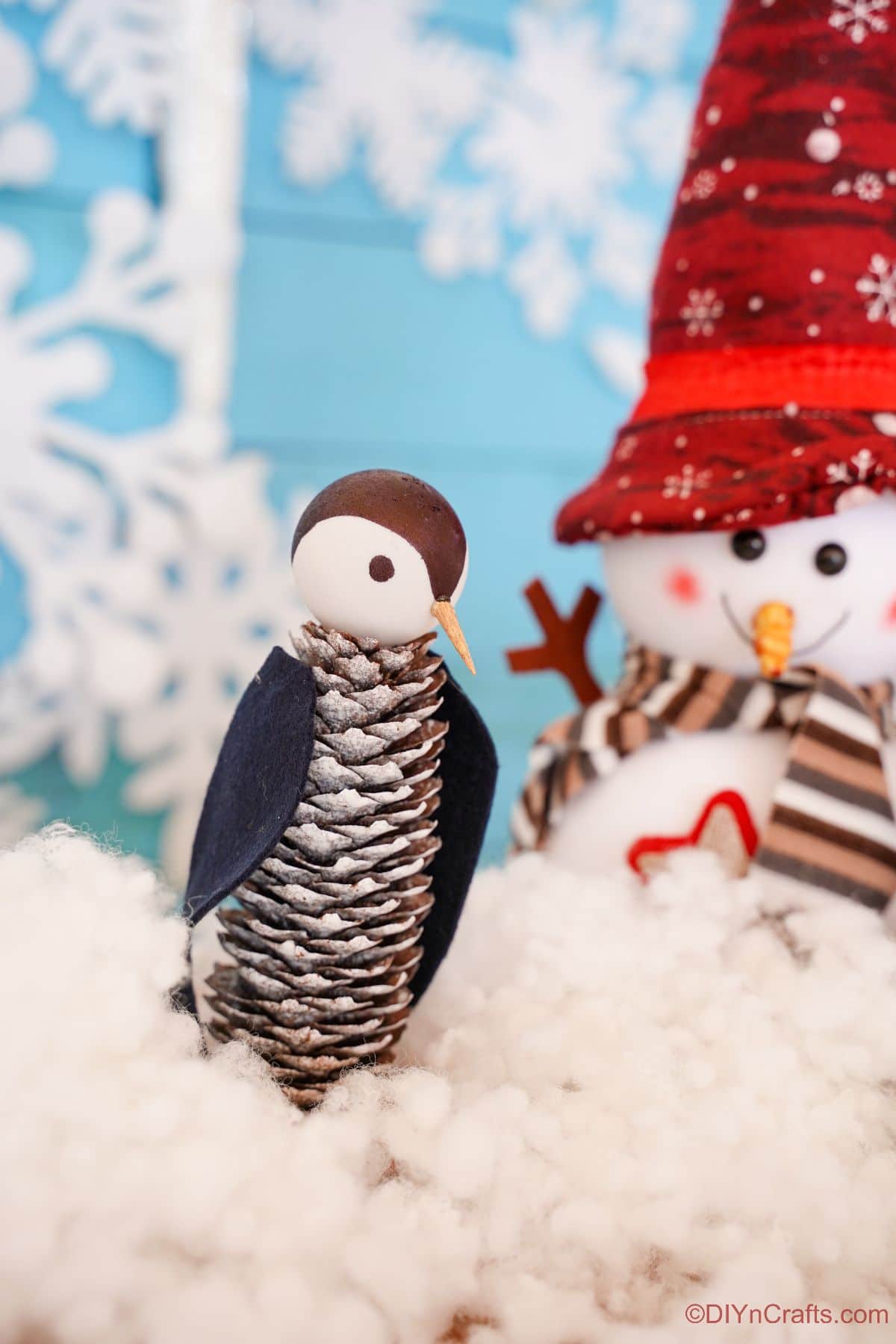 pinecone penguin on fake snow by snowman decoration
