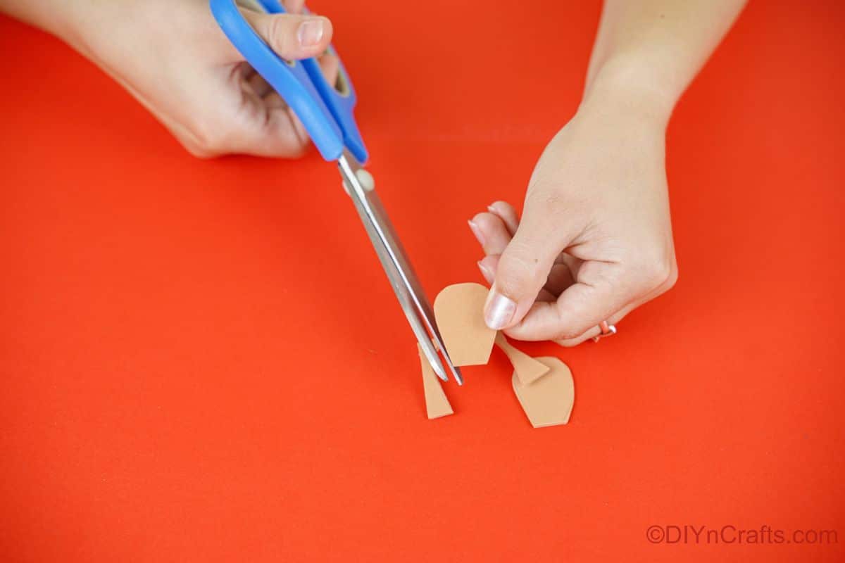 blue scissors cutting feet shape out of brown foam paper
