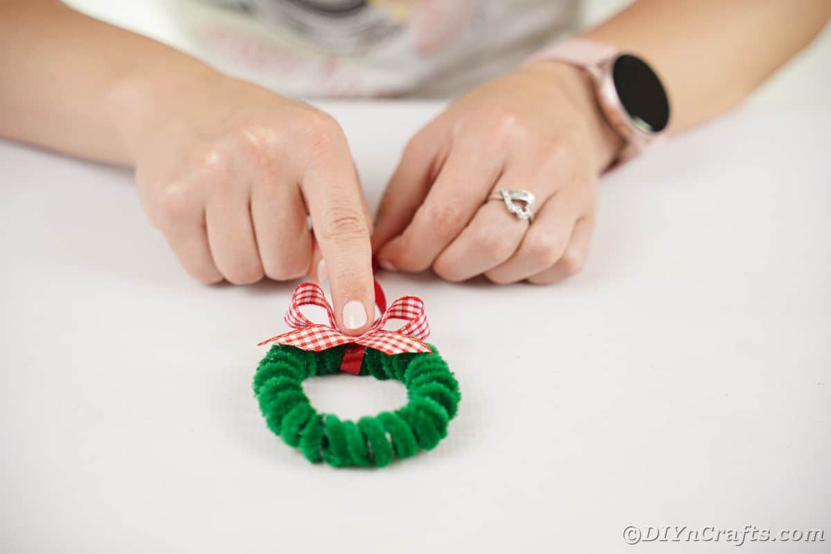 Hand holding bow on top of ornament