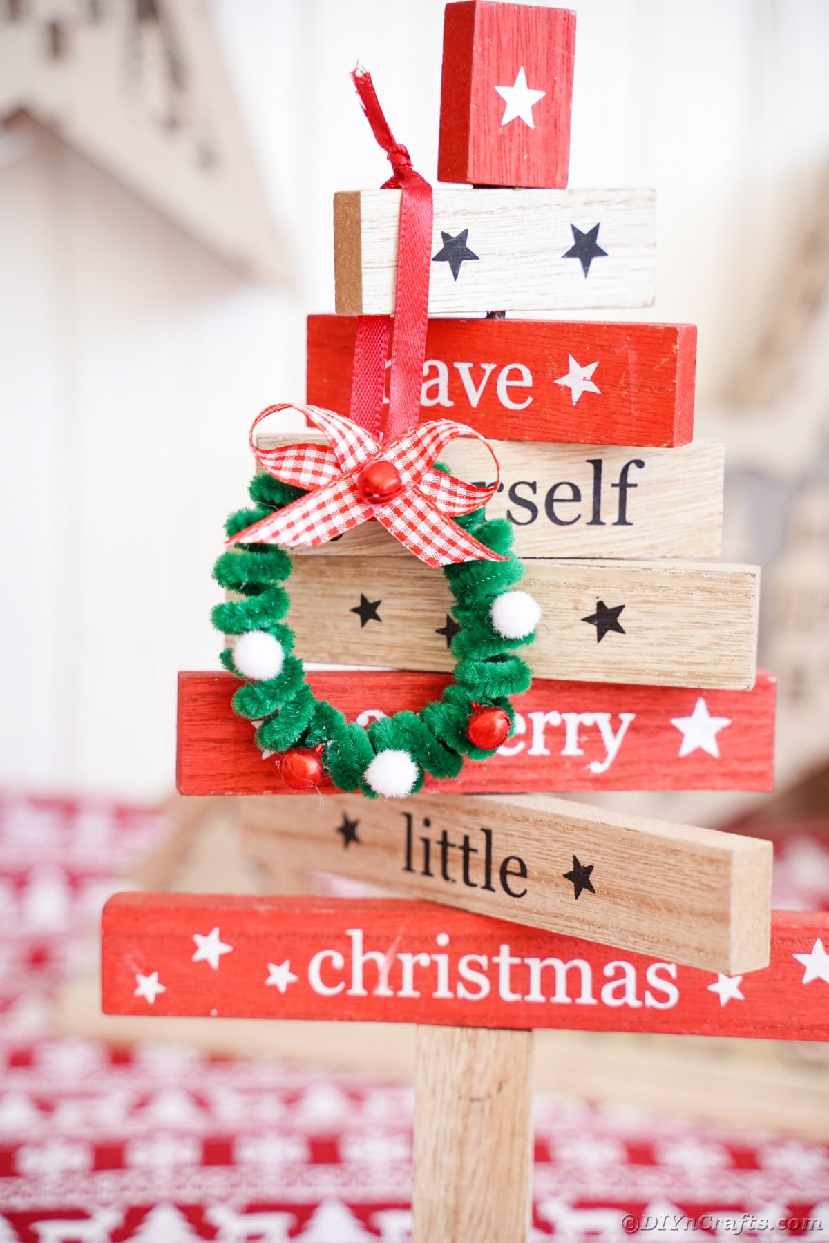 leseni blok božična dekoracija, ki drži miniaturni venec