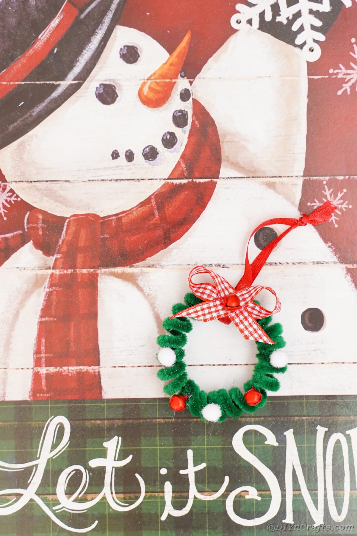 pipe cleaner wreath ornament against snowman sign