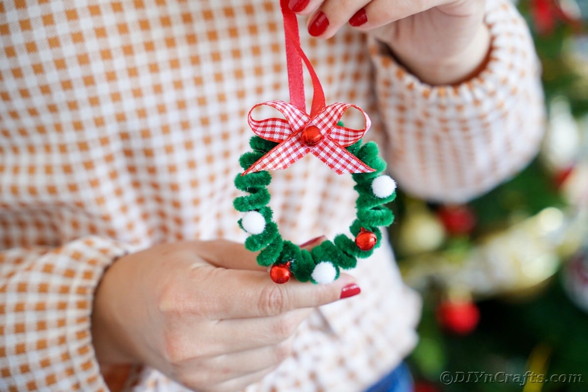 woman in checked shirt holding a mini wreath ornament